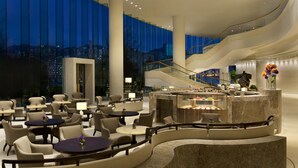 A modern hotel lobby with a central bar, seating areas, and a view of the cityscape. - Kerry Hotel Hong Kong by Shangri-la (Kowloon)