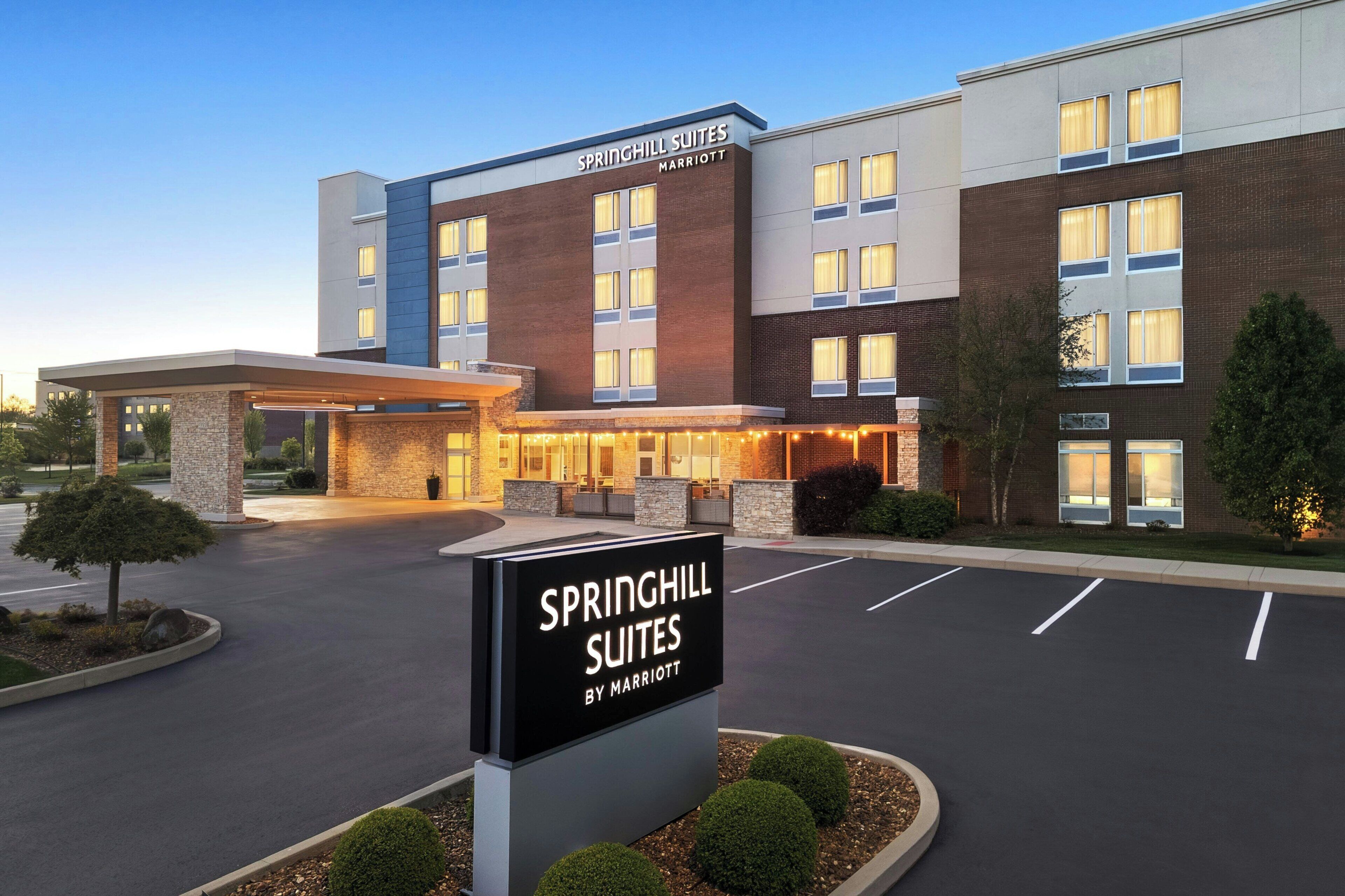 A hotel with a sign reading 'SPRINGHILL SUITES BY MARRIOTT,' a brick facade, and a parking lot.