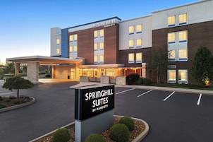 Un hotel con un letrero que dice 'SPRINGHILL SUITES BY MARRIOTT', fachada de ladrillo y estacionamiento.