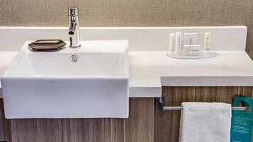 A bathroom with a white sink, a mirror, and a towel rack.