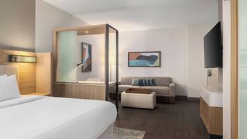 A hotel room with a bed, a sofa, a TV, and a wooden cabinet.
