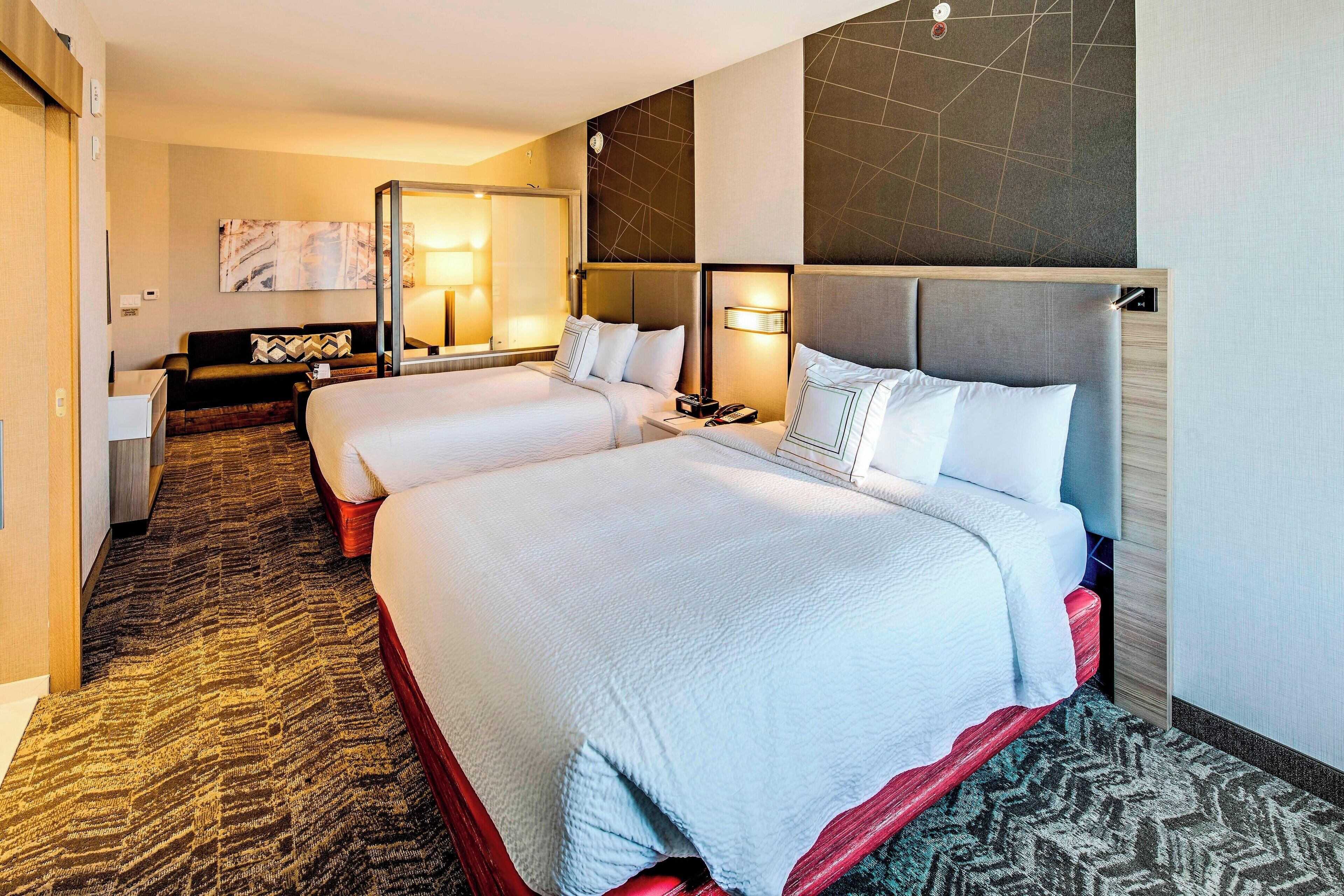 Une chambre d’hôtel avec deux lits, un canapé, un bureau et un miroir.