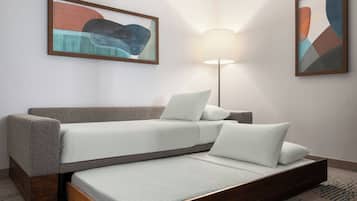 Una habitación con sofá cama, una lámpara de pie y dos cuadros abstractos en la pared.