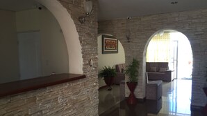 Amplia sala de estar con pared de piedra, mostrador de recepción de madera, sofá y mesa de centro.