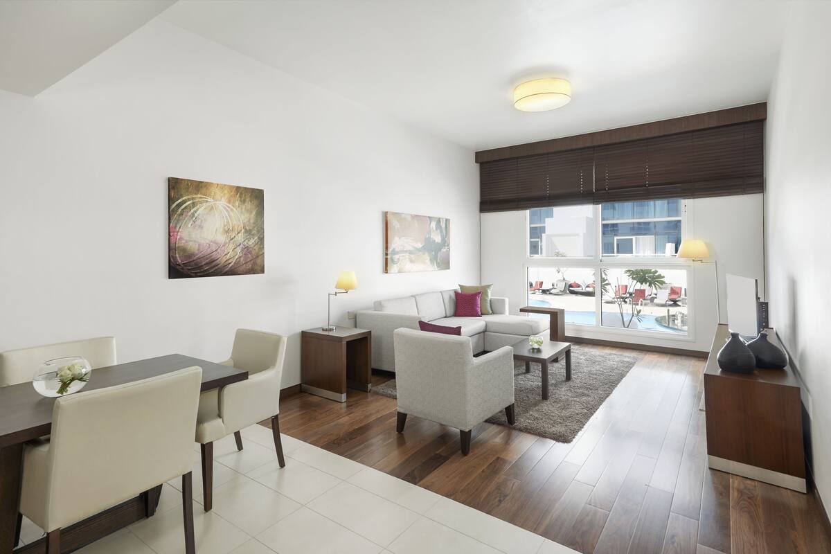 A modern living room with a dining area, large windows, and artwork on the walls.