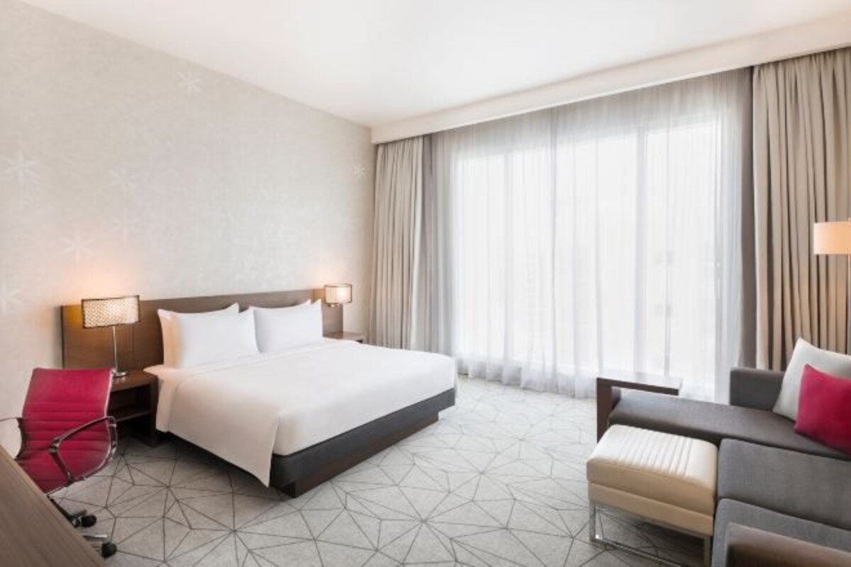 Une chambre d’hôtel avec un grand lit, des lampes de chevet, un bureau et une chaise.
