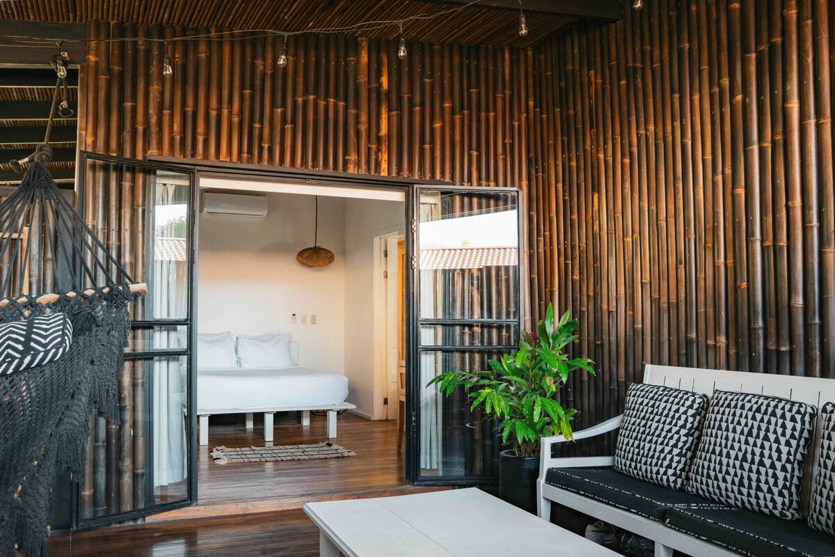 Un intérieur moderne avec un lit, un canapé et une plante suspendue.
