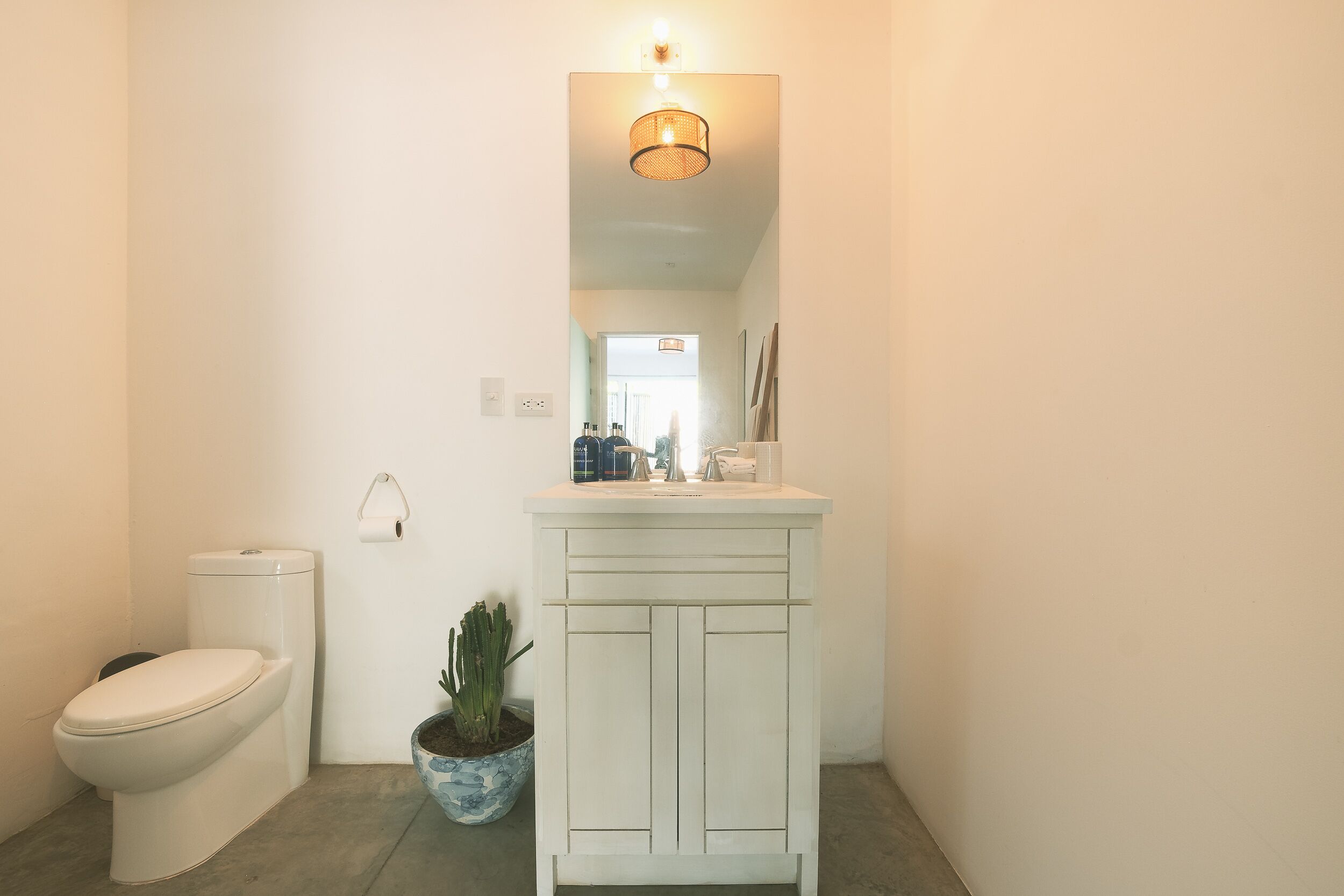 A small bathroom with a toilet, a sink, and a mirror.