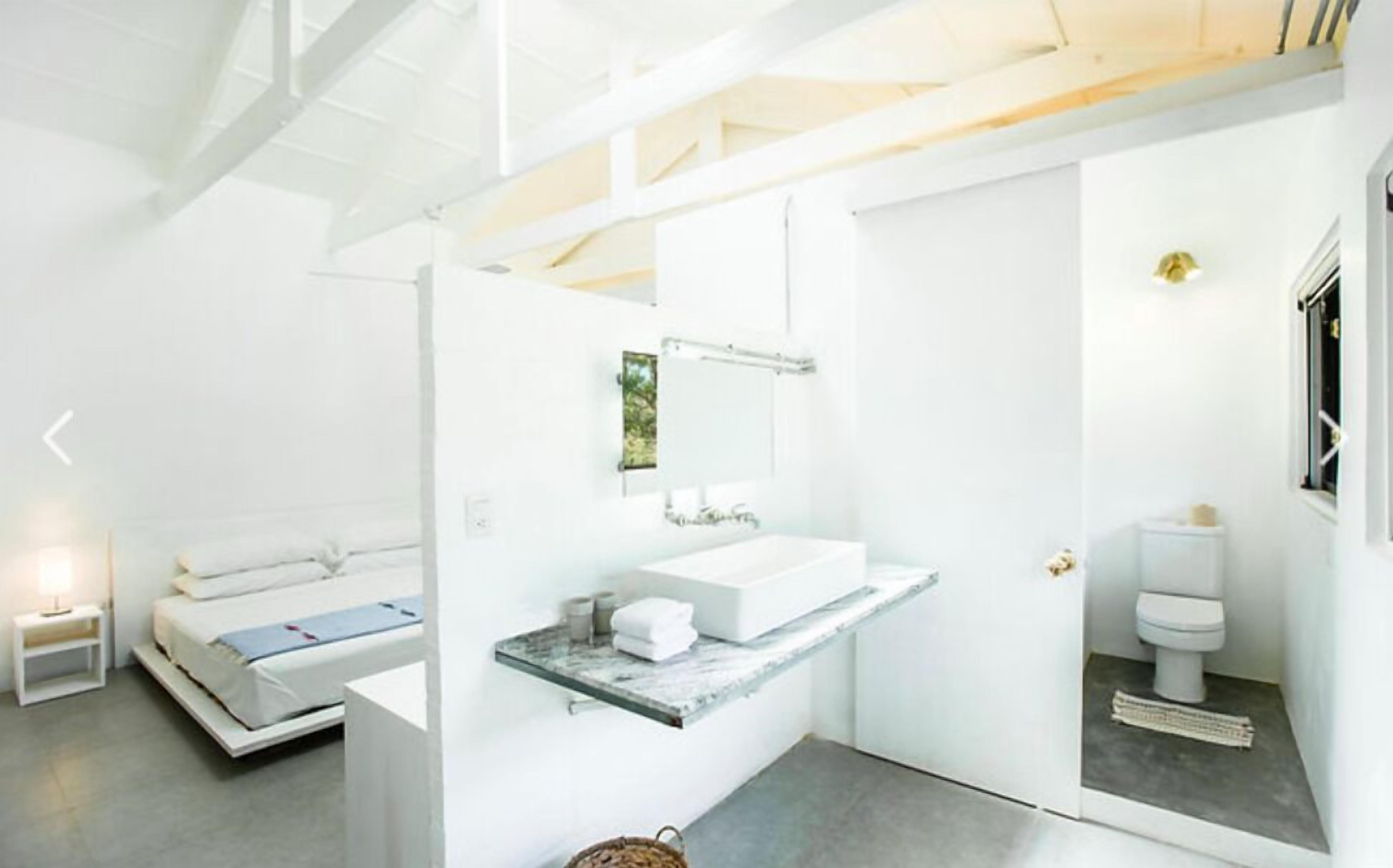 A modern bathroom with a large mirror, a white sink, and a toilet.