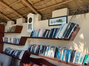 Una habitación con estanterías de madera llenas de libros, un pequeño adorno blanco y un cuadro en la pared.
