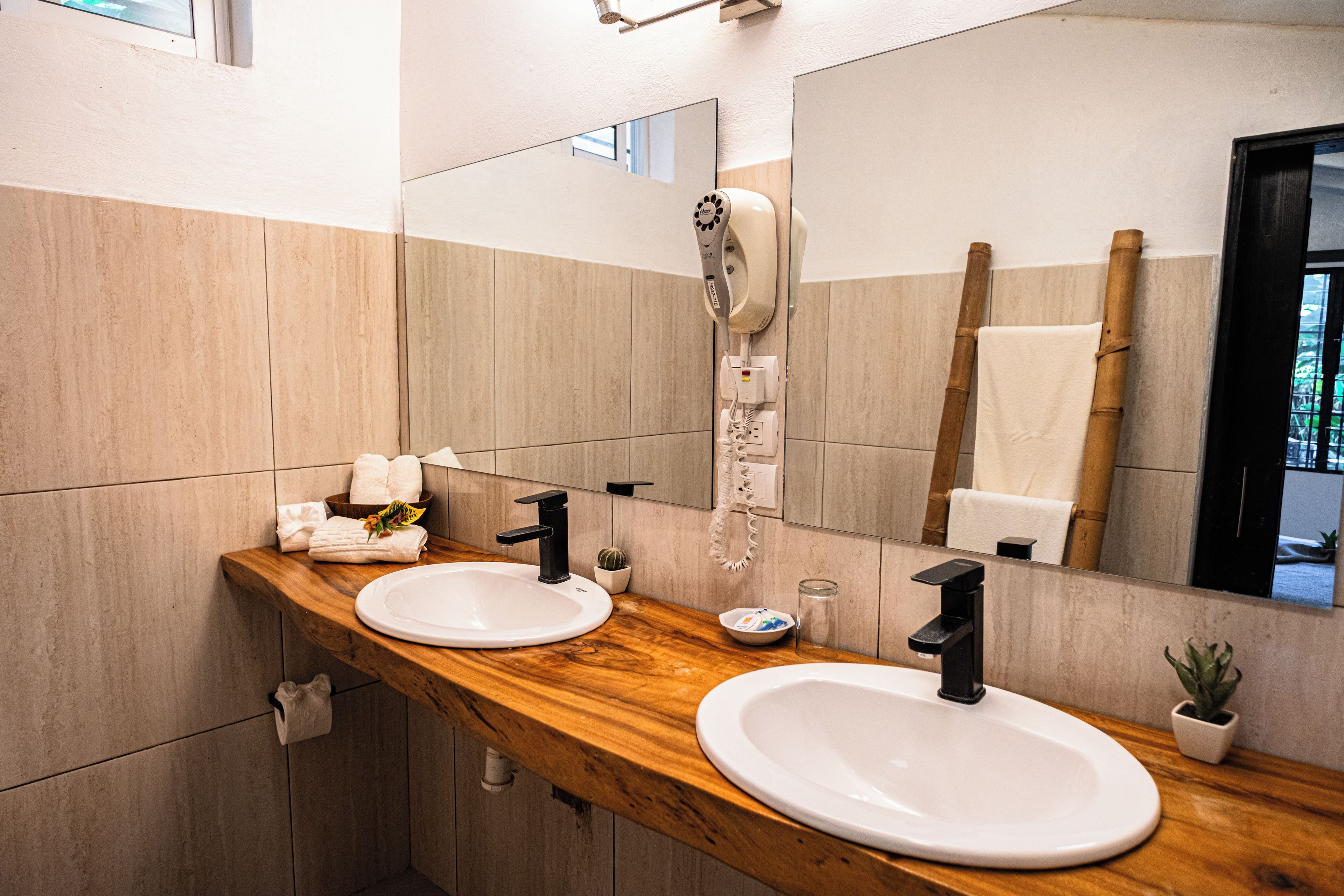 Un baño con dos lavamanos, un secador de pelo y un espejo.