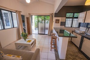 Cocina compacta con comedor, una pequeña mesa con planta y un sofá.