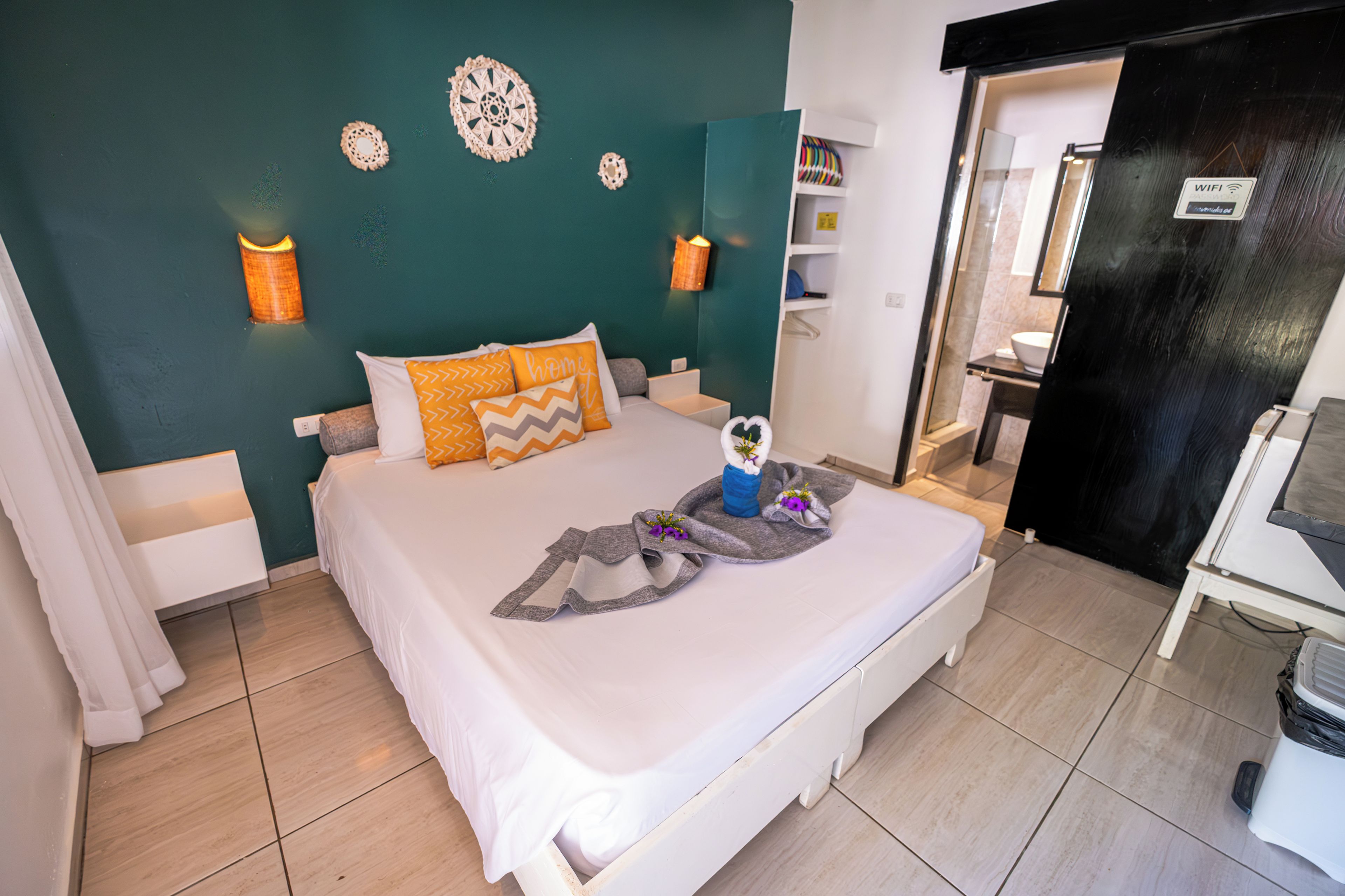 Una habitación de hotel con cama, lámparas de noche, baño y puerta.