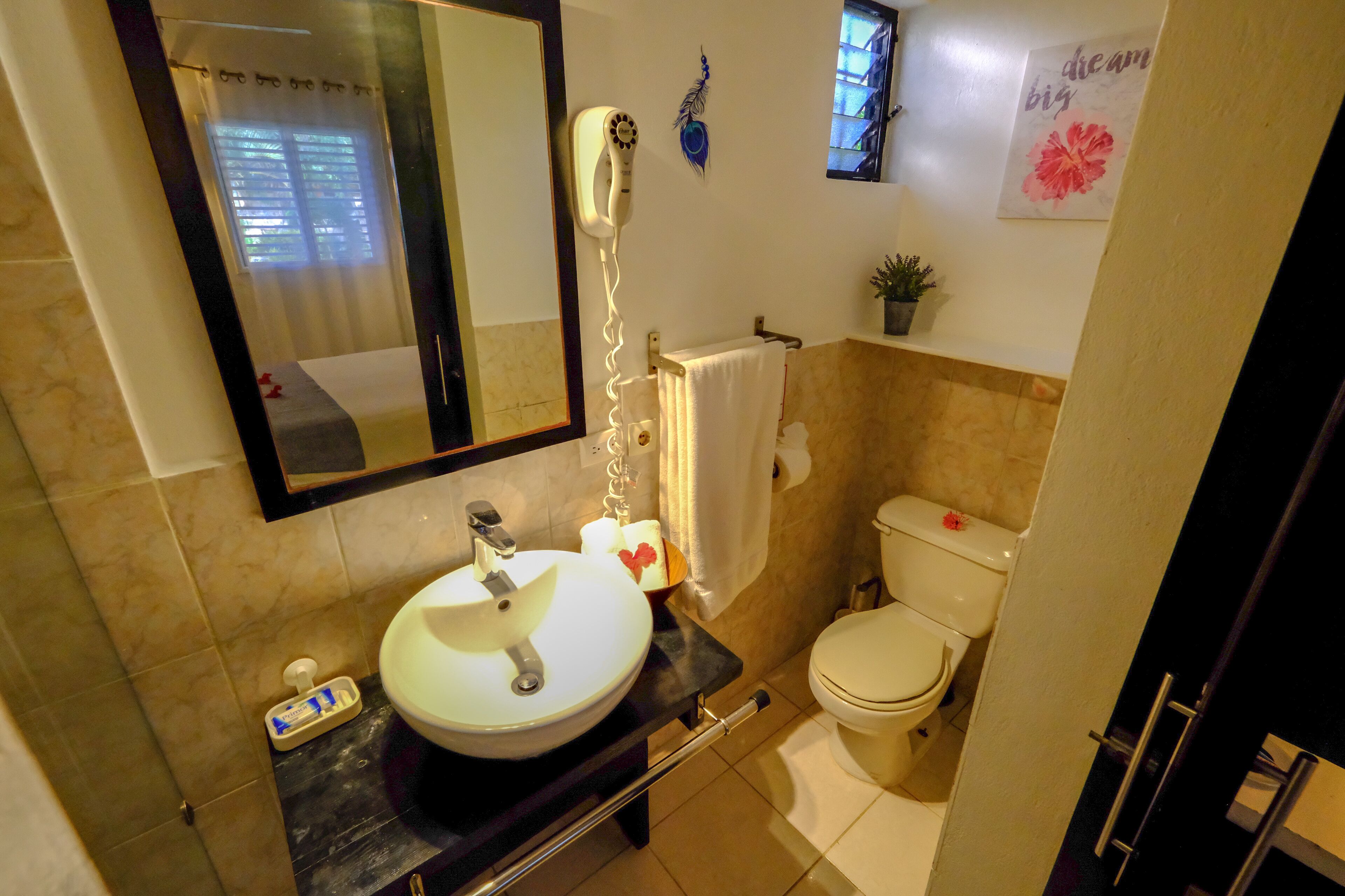 A bathroom with a sink, toilet, and a hairdryer on the wall.
