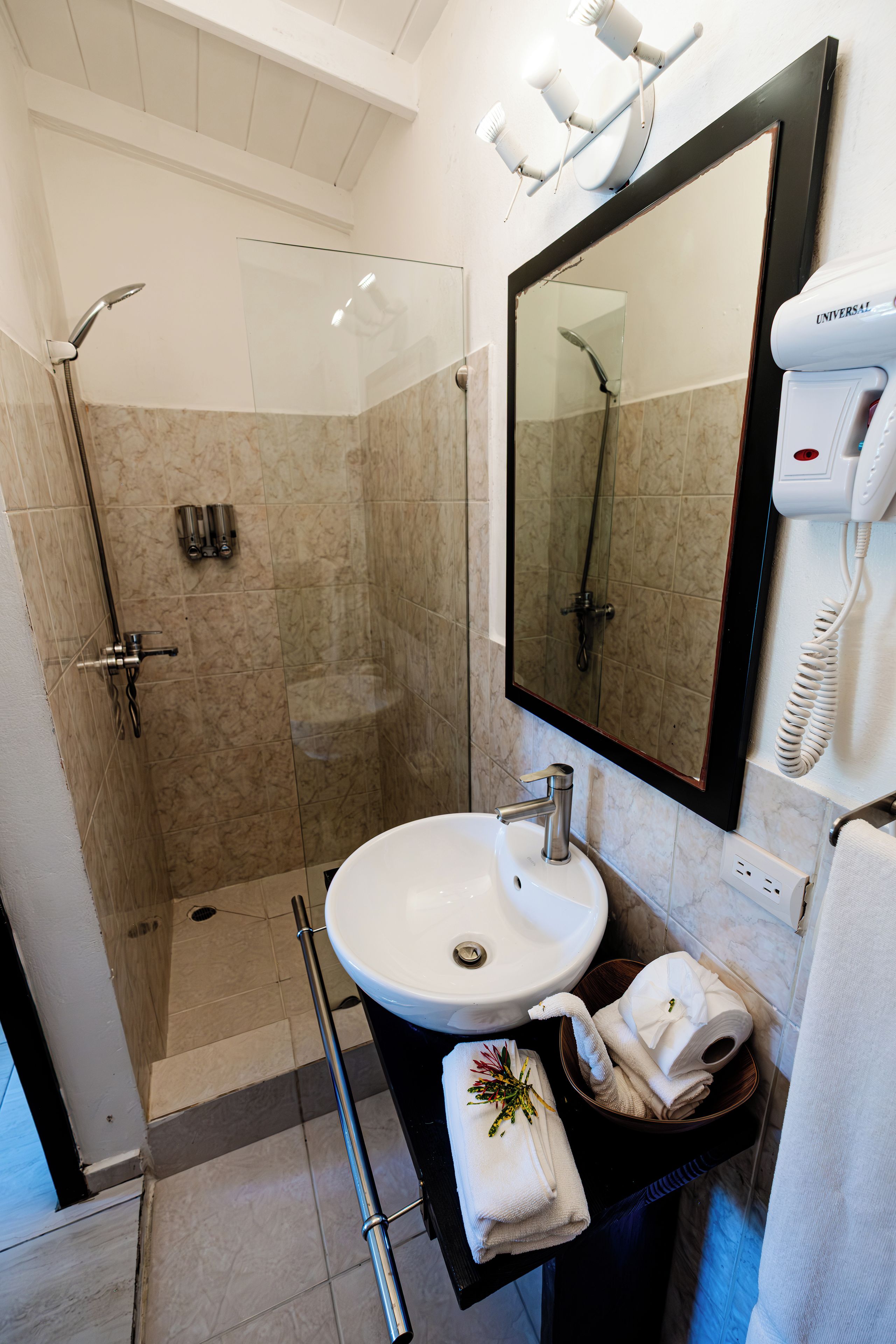 Un bagno moderno con doccia vetro, lavandino bianco e uno specchio grande.