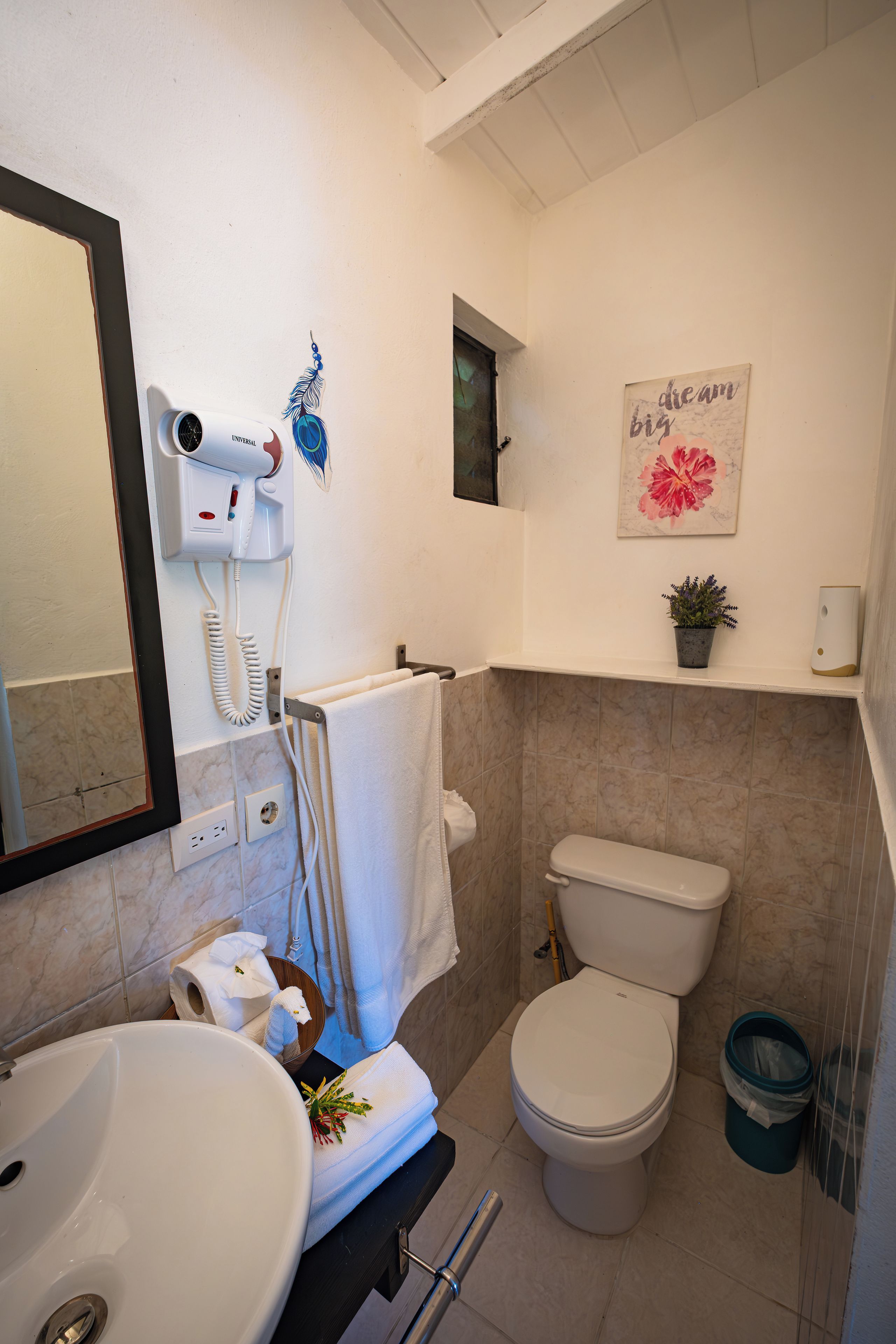 A bathroom with a toilet, sink, and a hairdryer mounted on the wall.