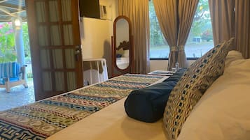Ein Schlafzimmer mit einem großen Bett, einem Nachttisch, einem Spiegel und Blick ins Freie.