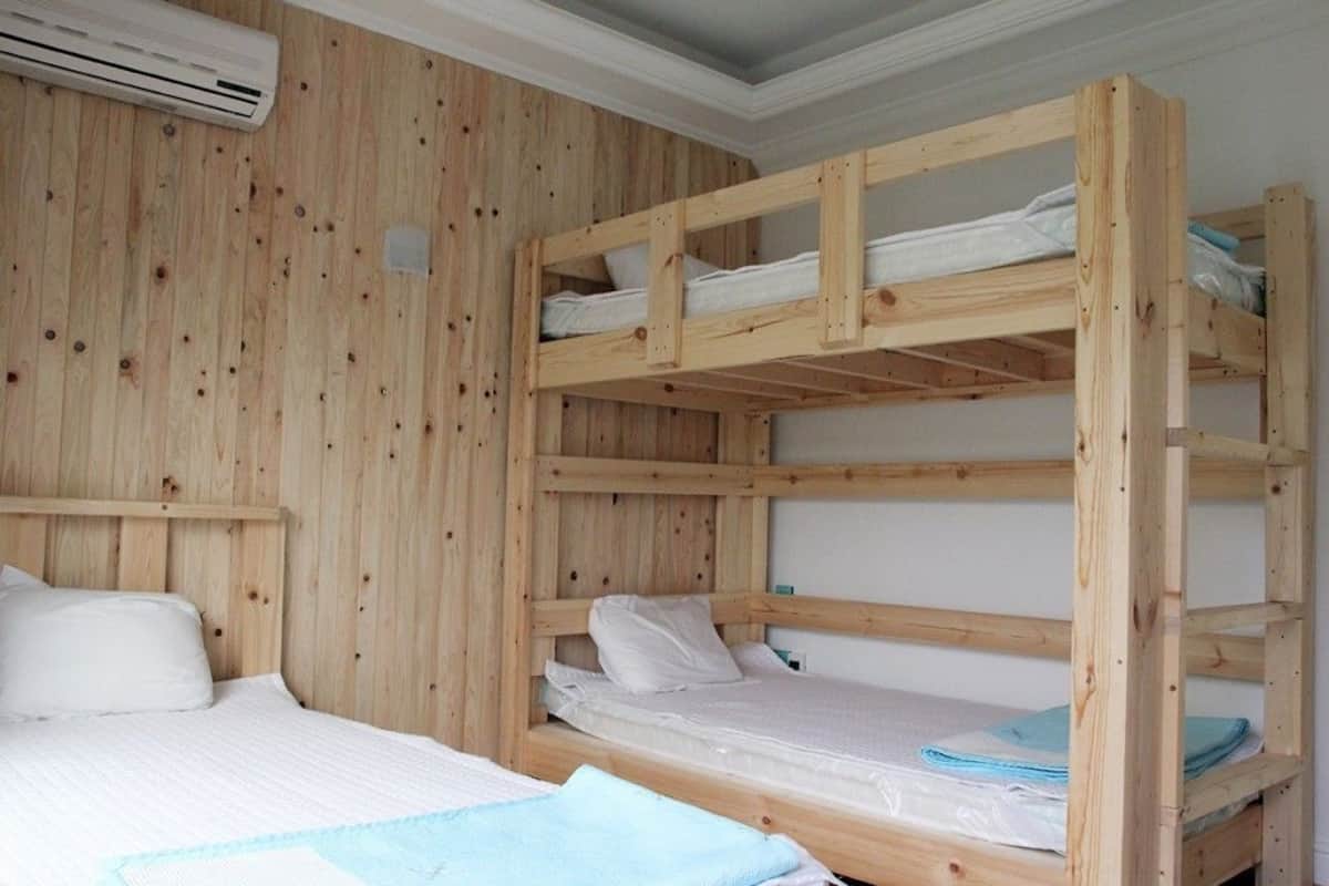 Dormitorio con literas, paredes de madera y un equipo de aire acondicionado.