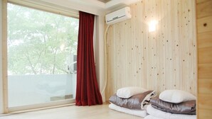 Ein Zimmer mit großem Fenster, einer Holzwand und einem Bett mit Kissen.