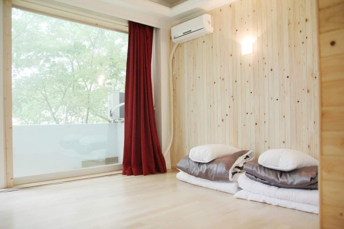 Una habitación con un ventanal grande, un muro de madera y una cama con almohadas.