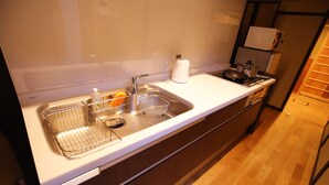 A kitchen with a stainless steel sink, a kettle, and a microwave. - Machiya AND (Kyoto)