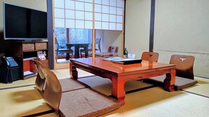 A traditional Japanese-style room with tatami flooring, a low wooden table, and a television on the left. - Machiya AND (Kyoto)