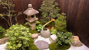 A garden with a stone lantern, rocks, and various plants. - Machiya AND (Kyoto)