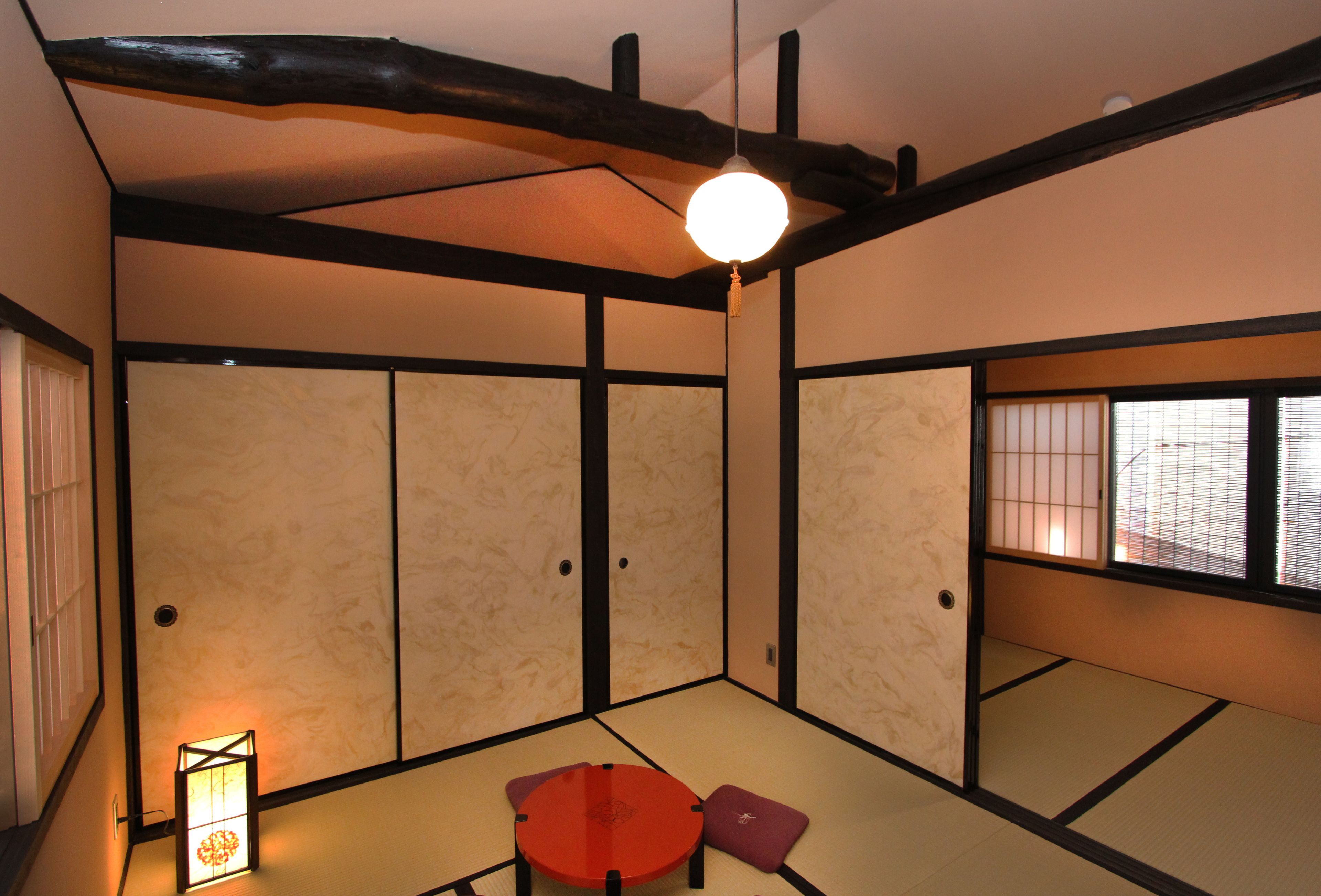 A traditional Japanese room with tatami flooring, a low table with cushions, and sliding doors.