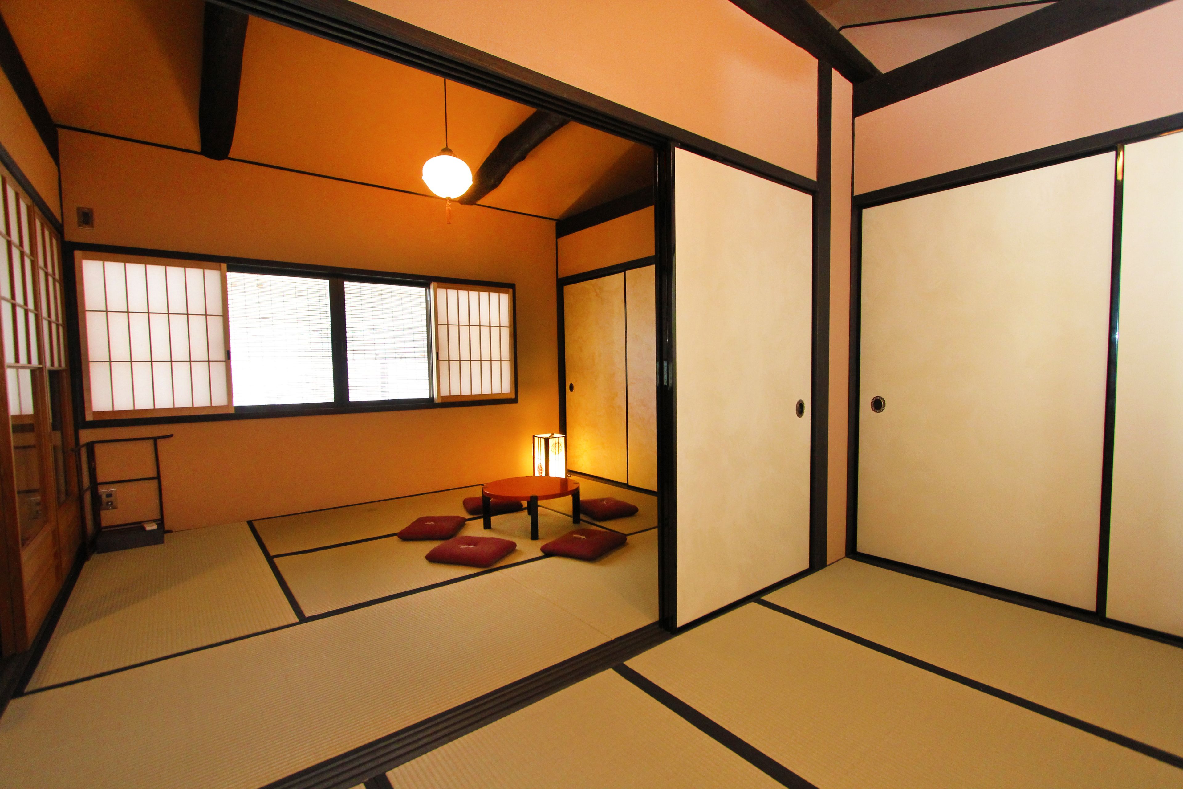 A traditional Japanese room with tatami flooring, sliding doors, and a low table with cushions.