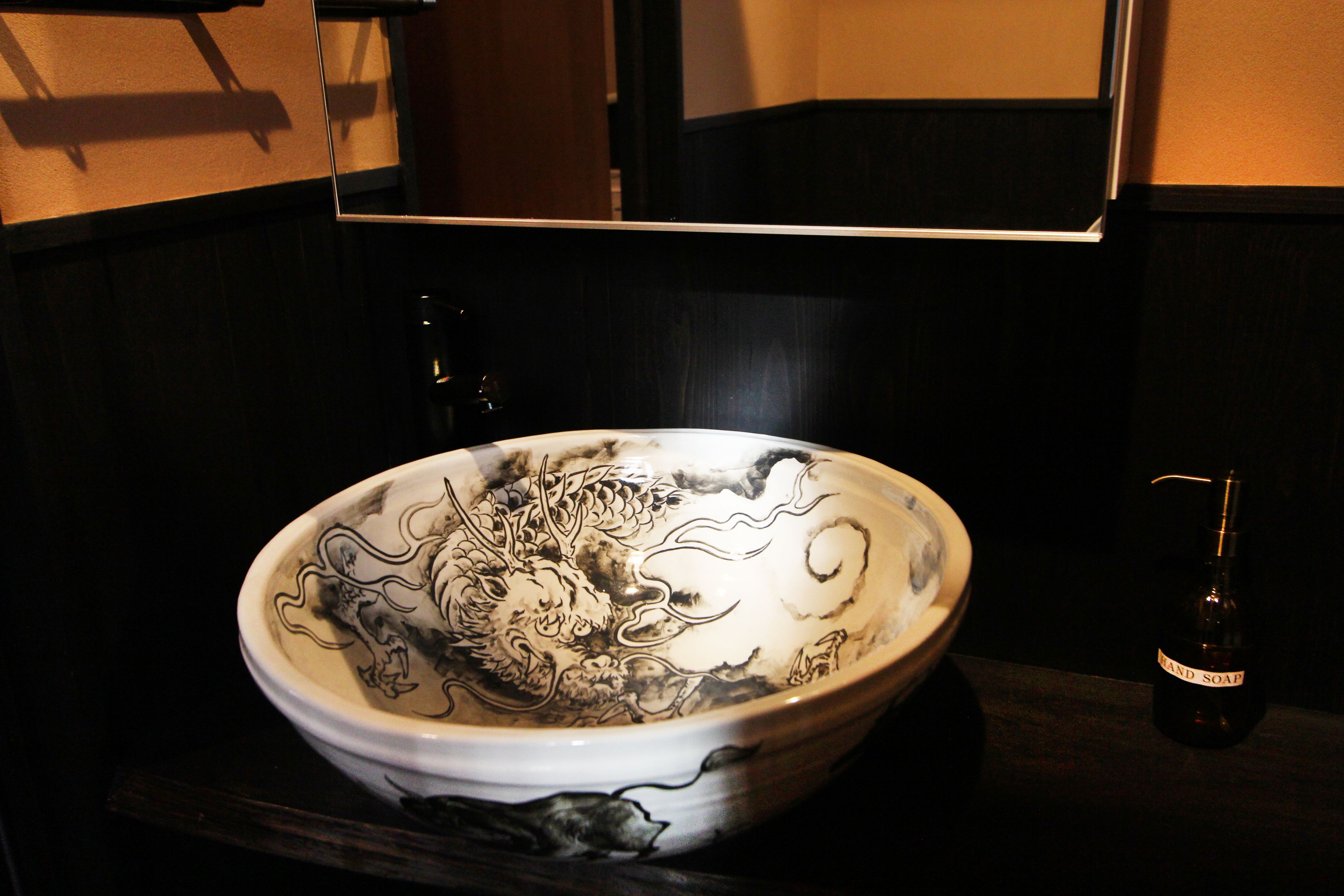 A ceramic bowl with a dragon design on a dark countertop.