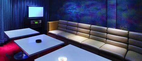 A cozy cinema room with a plush sofa, a large screen, and a snack table.
