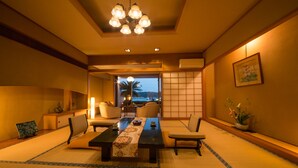 A traditional Japanese-style room with tatami flooring, a low table with a table runner, and a view of the sea. - Kurofune Hotel (Shimoda)