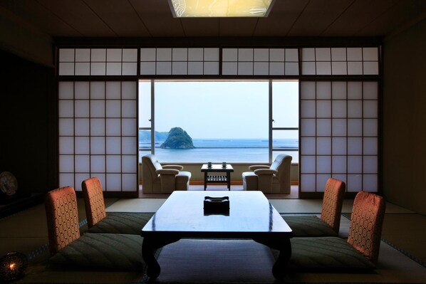 Ein traditioneller japanischer Raum mit Tatami-Böden, einem niedrigen Tisch und Meerblick durch Shoji-Schirme.