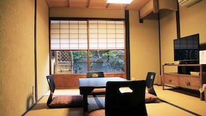 A traditional Japanese room with tatami flooring, a low table, and a television on a wooden stand. - Demizu Machiya (Kyoto)
