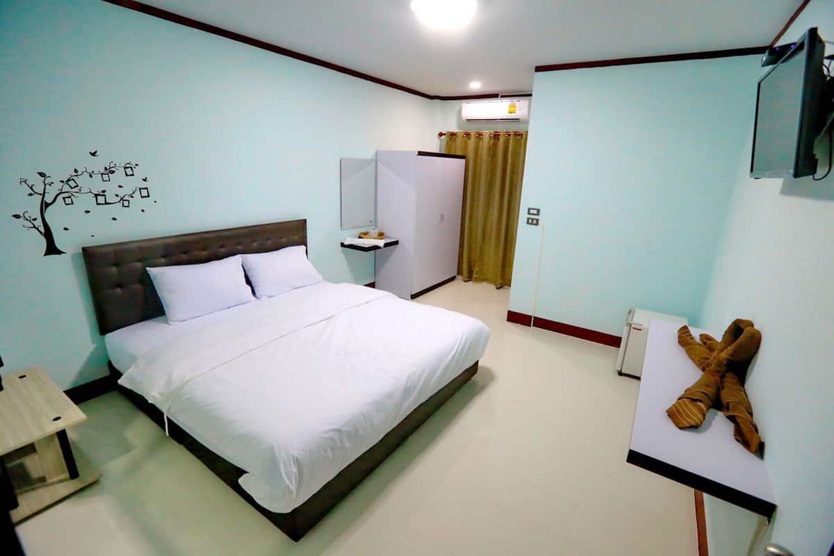 Quarto com cama, mesa de cabeceira, guarda-roupa, espelho e televisão.