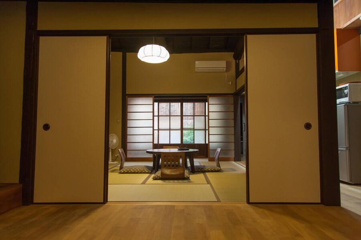 Ett traditionellt japanskt rum med tatamimattor på golvet, en shojiskärm, ett bord med tatamimatta som bordsyta och en takfläkt.