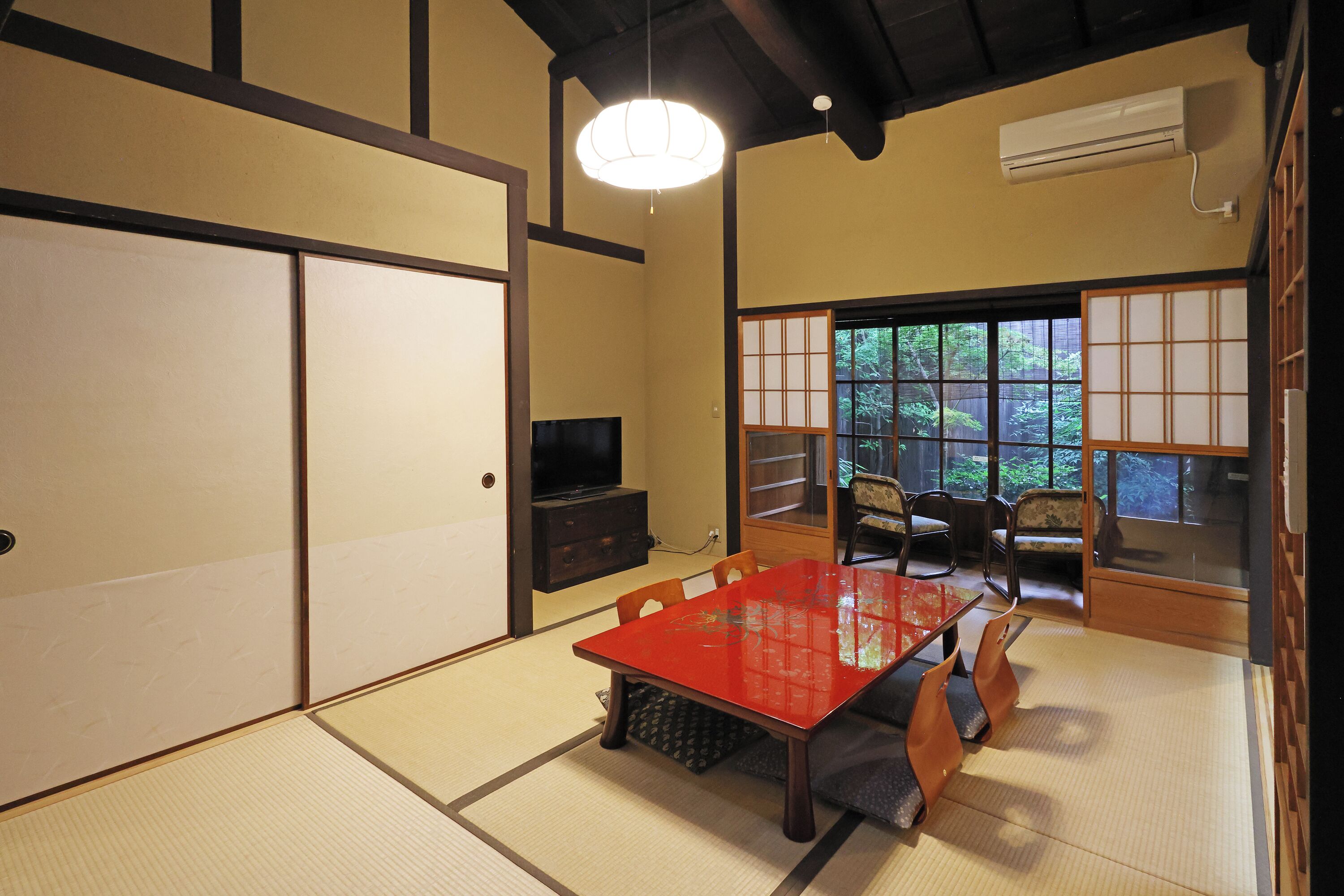 Una habitación tradicional japonesa con suelo de tatami, una mesa roja y puertas correderas.