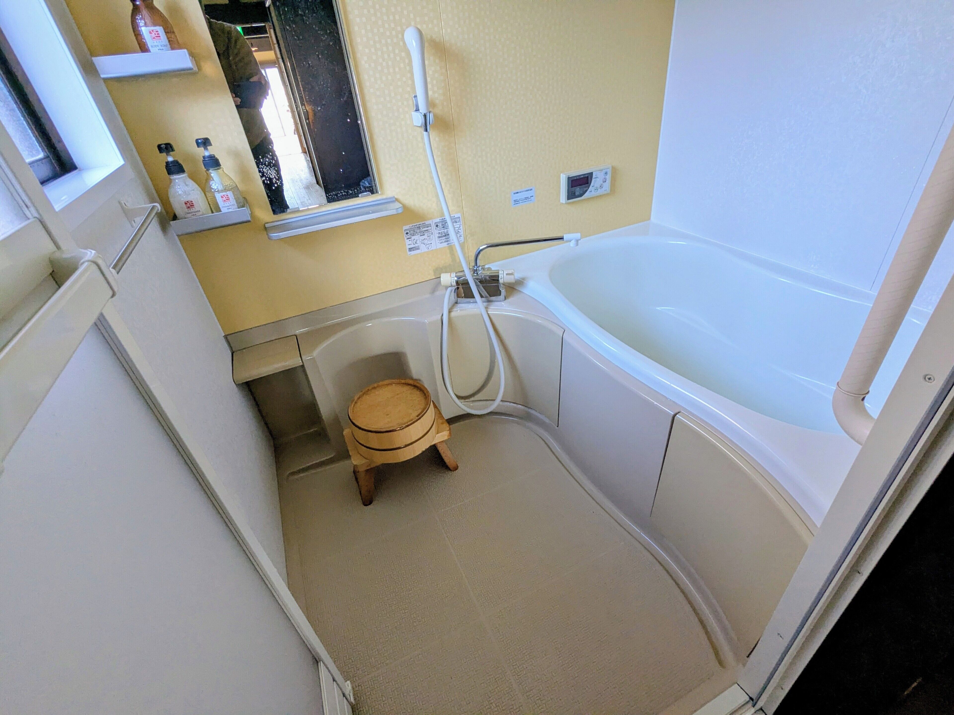 Une petite salle de bain comprenant une baignoire, un petit tabouret en bois et des toilettes.
