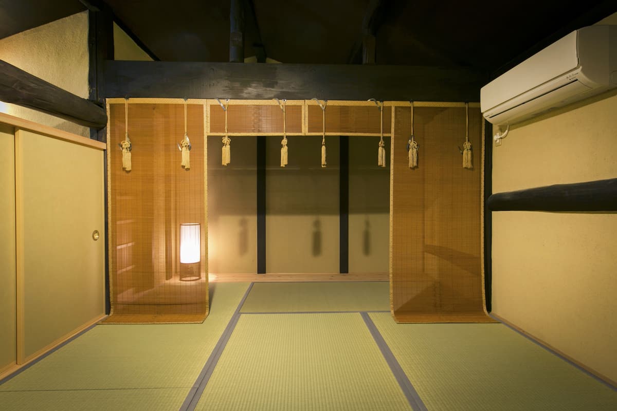 Ett traditionellt japanskt rum med tatamimattor på golvet, skjutdörrar och en hängande lykta.