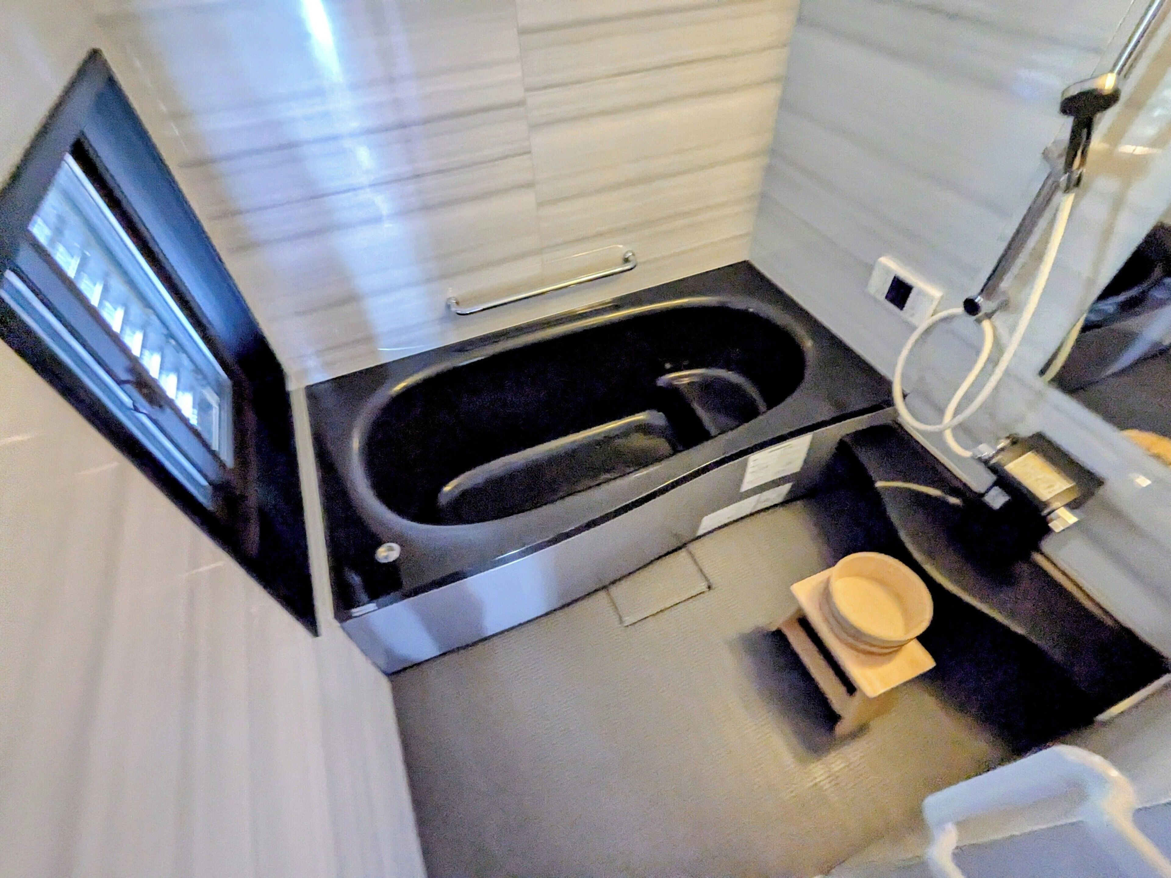 Een moderne badkamer met een zwart bad, toilet en douche.