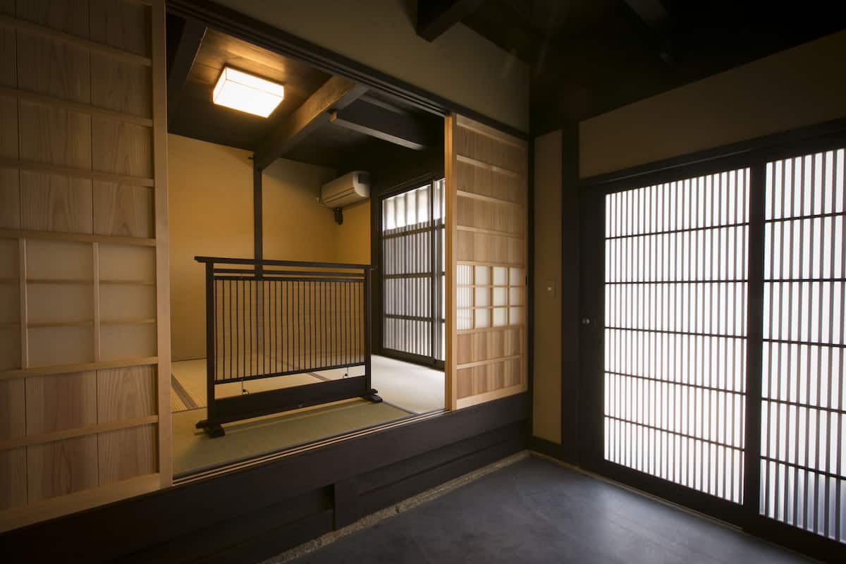 Ett traditionellt japanskt rum med tatamimattor på golvet, skjutdörrar och en låg träbänk.