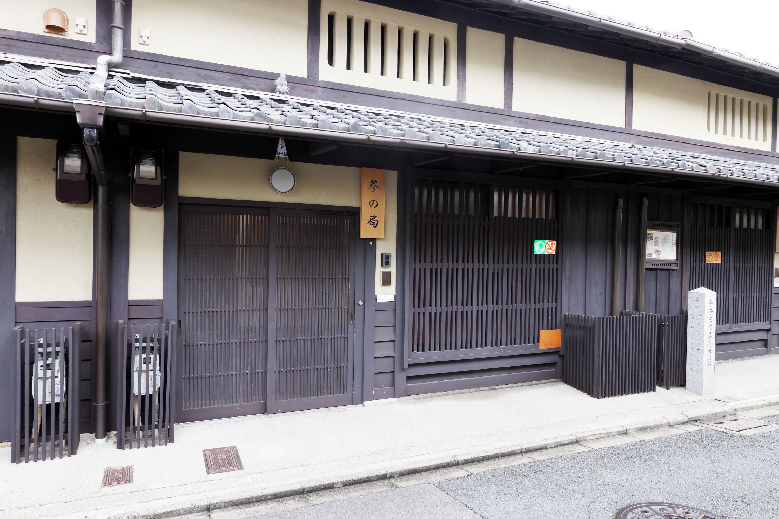 A traditional Japanese building with a tiled roof, dark wooden doors, and a sign indicating a restaurant.