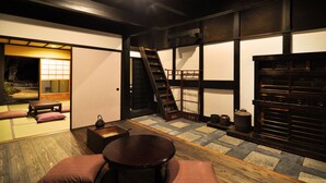 Un interior japonés tradicional con suelo de tatami, una mesa de madera baja, cojines, una puerta corredera y una chimenea empotrada.