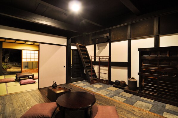 A traditional Japanese interior with tatami flooring, a low wooden table, cushions, a sliding door, and a built-in fireplace. - Shirafuji-an (Kyoto)