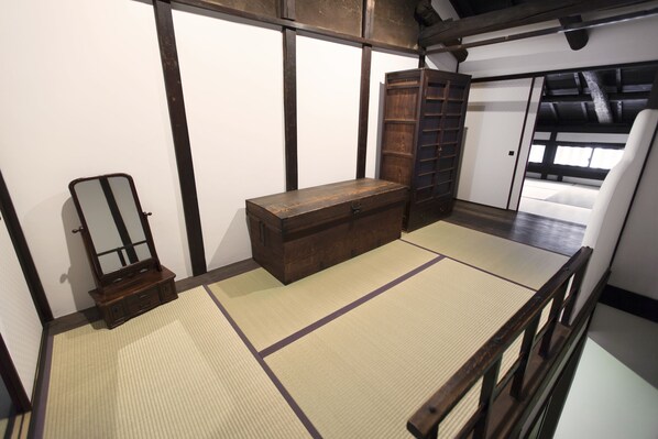 Et traditionelt japansk rum med tatamimåtter, et træskab, et spejl og en skydedør.