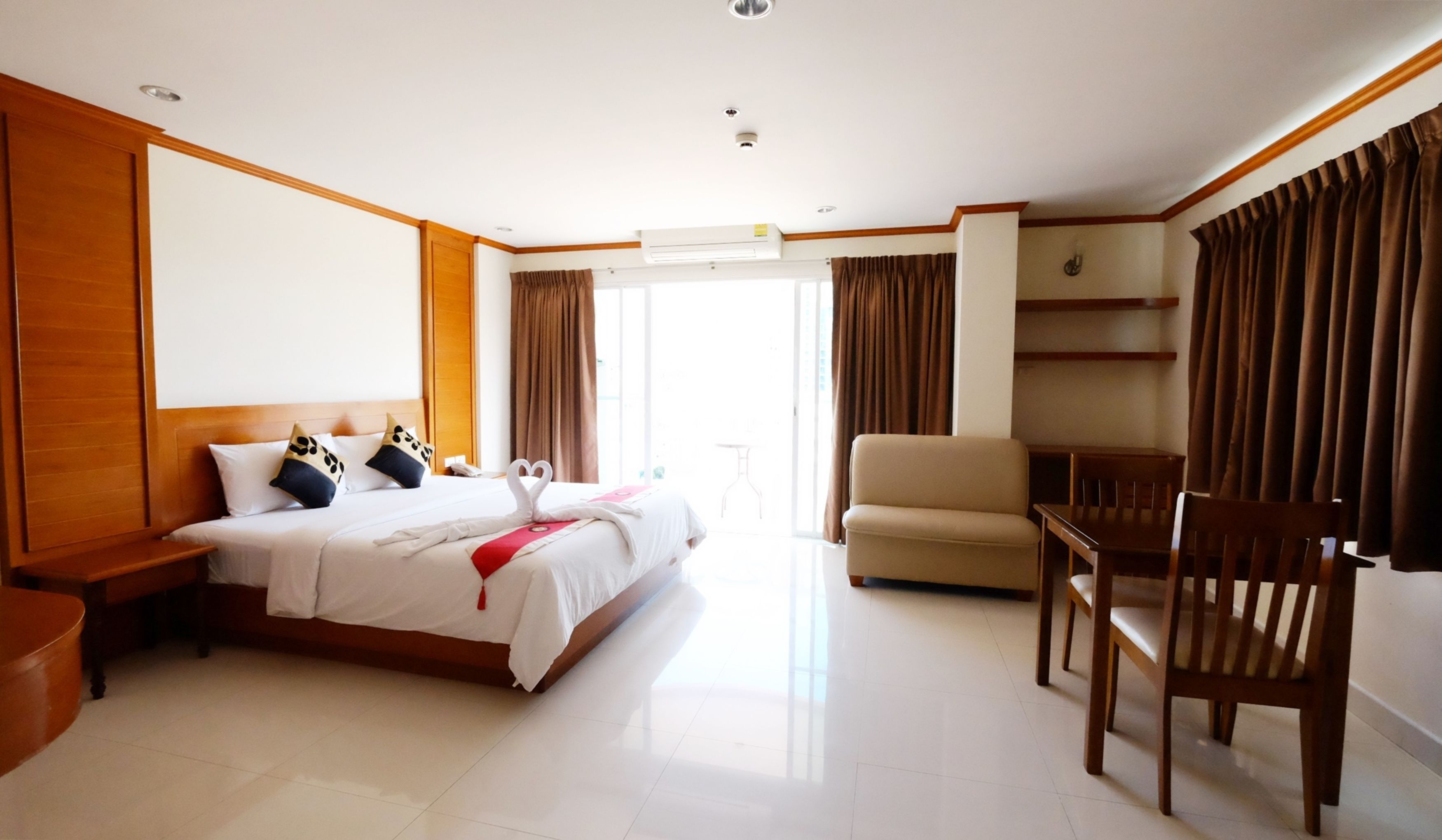 A hotel room with a bed, a chair, a desk, and a large window.