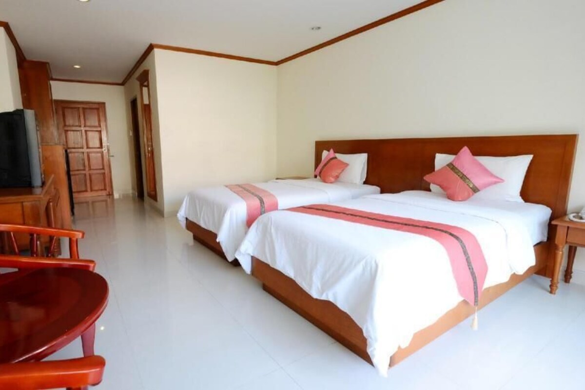 A hotel room with two beds, a TV, a desk, and a chair.