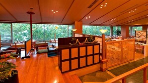 A spacious hotel lobby with wooden flooring, a reception desk, and large windows offering a view of greenery outside. - Ryokan Tokiichiyu (Minamiizu)