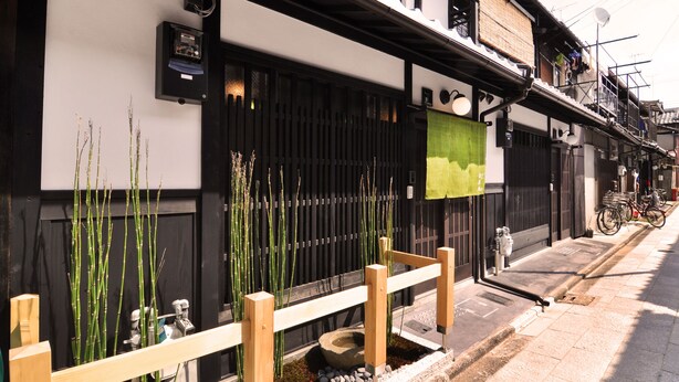 Ein traditionelles japanisches Gebäude mit schwarzem Tor, Holzpforte und Bambuspflanzen.