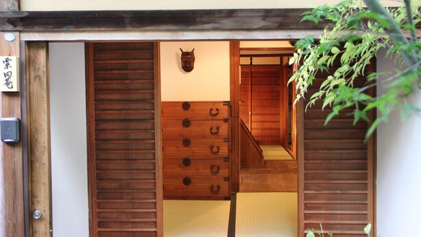 Una habitación japonesa tradicional con suelo de tatami, puerta corredera de madera y pantalla shoji.